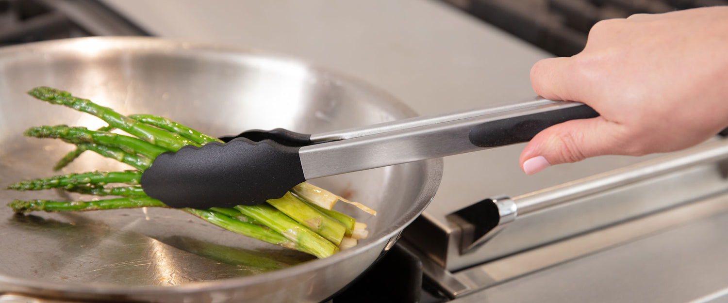 Gorilla Grip kitchen tongs being used to cook asparagus on a stovetop